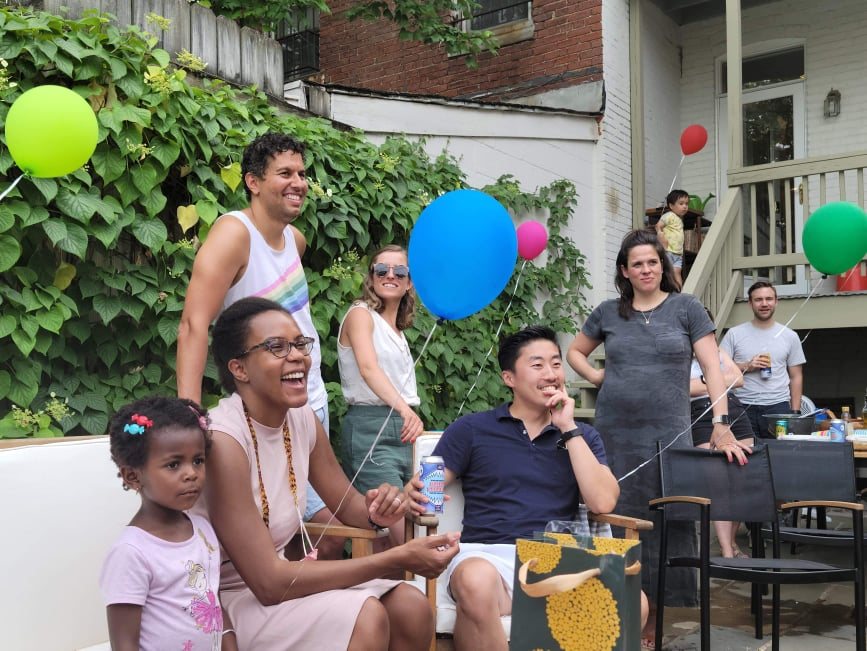 Parents and kids laughing together under the balloons at a backyard birthday party