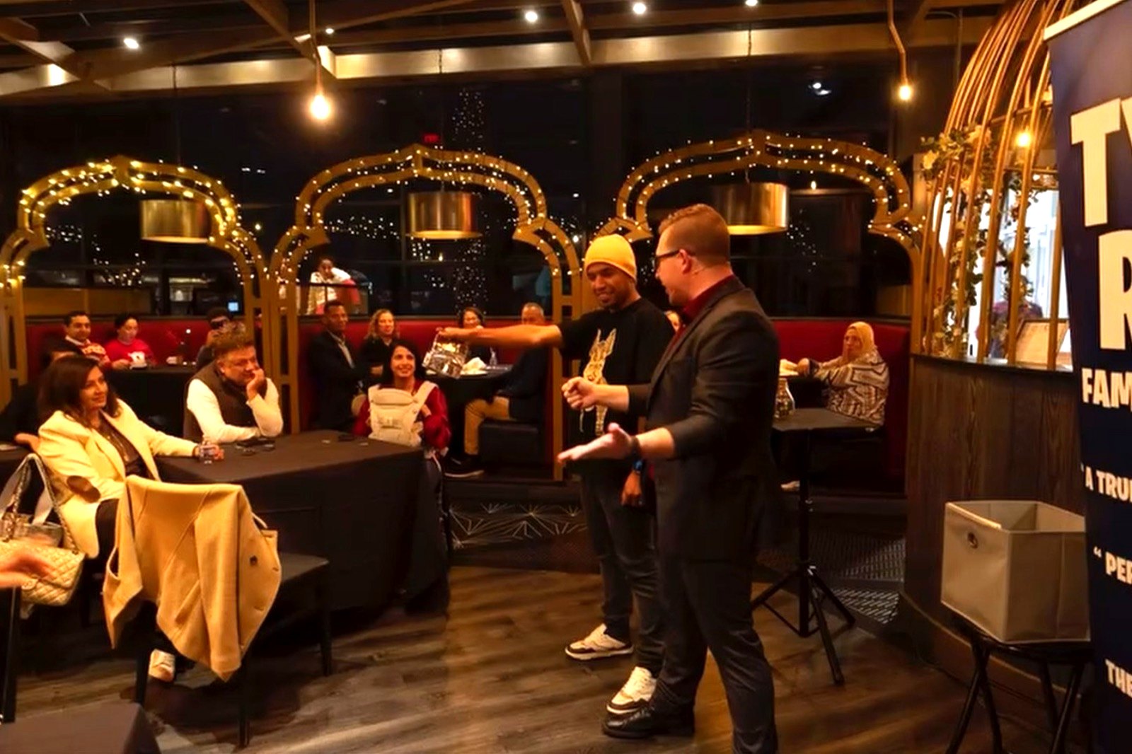 A holiday party crowd watches Tyler bring a guest into the act