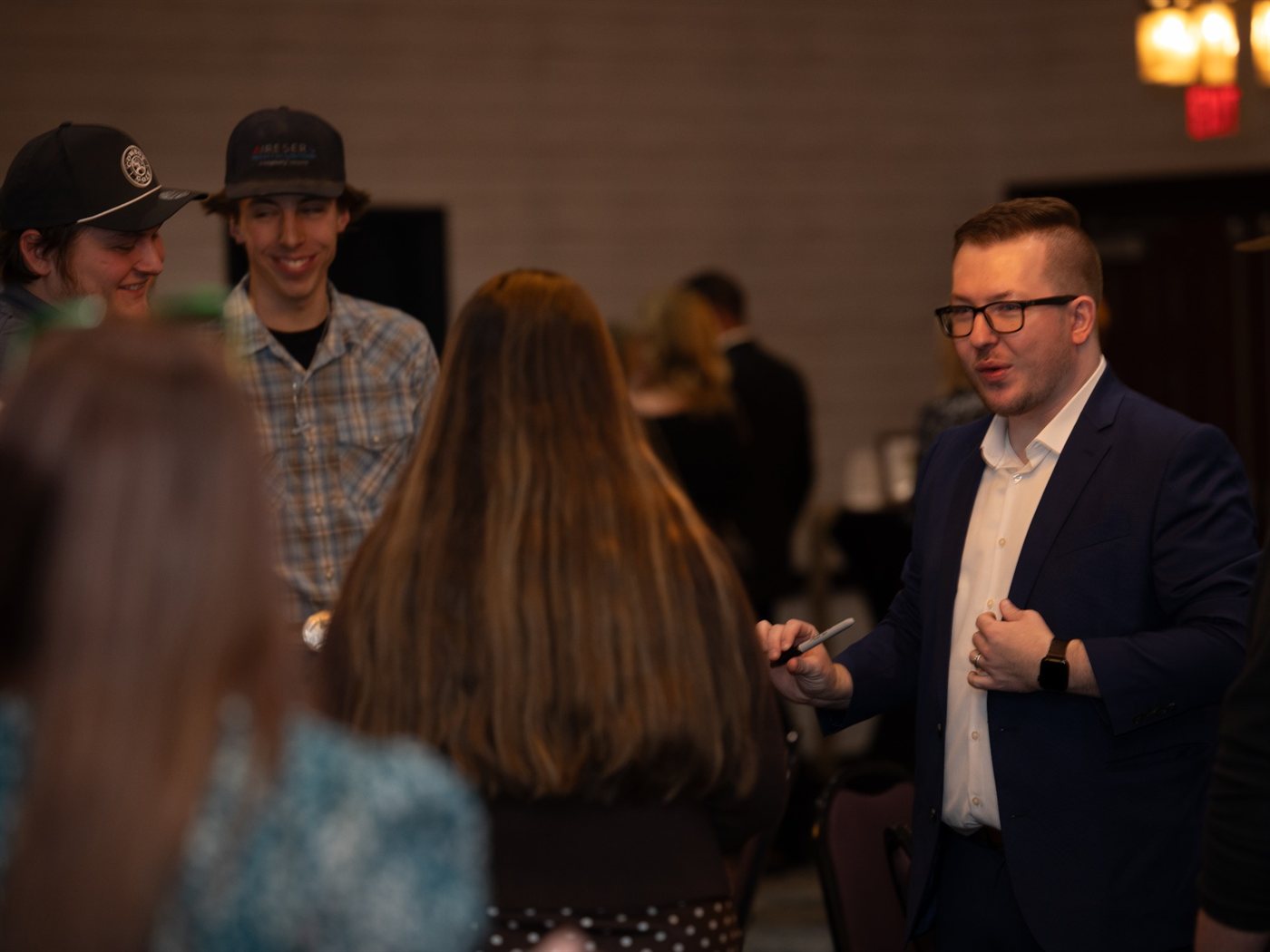Tyler performs close-up magic for a delighted circle of guests during a holiday reception