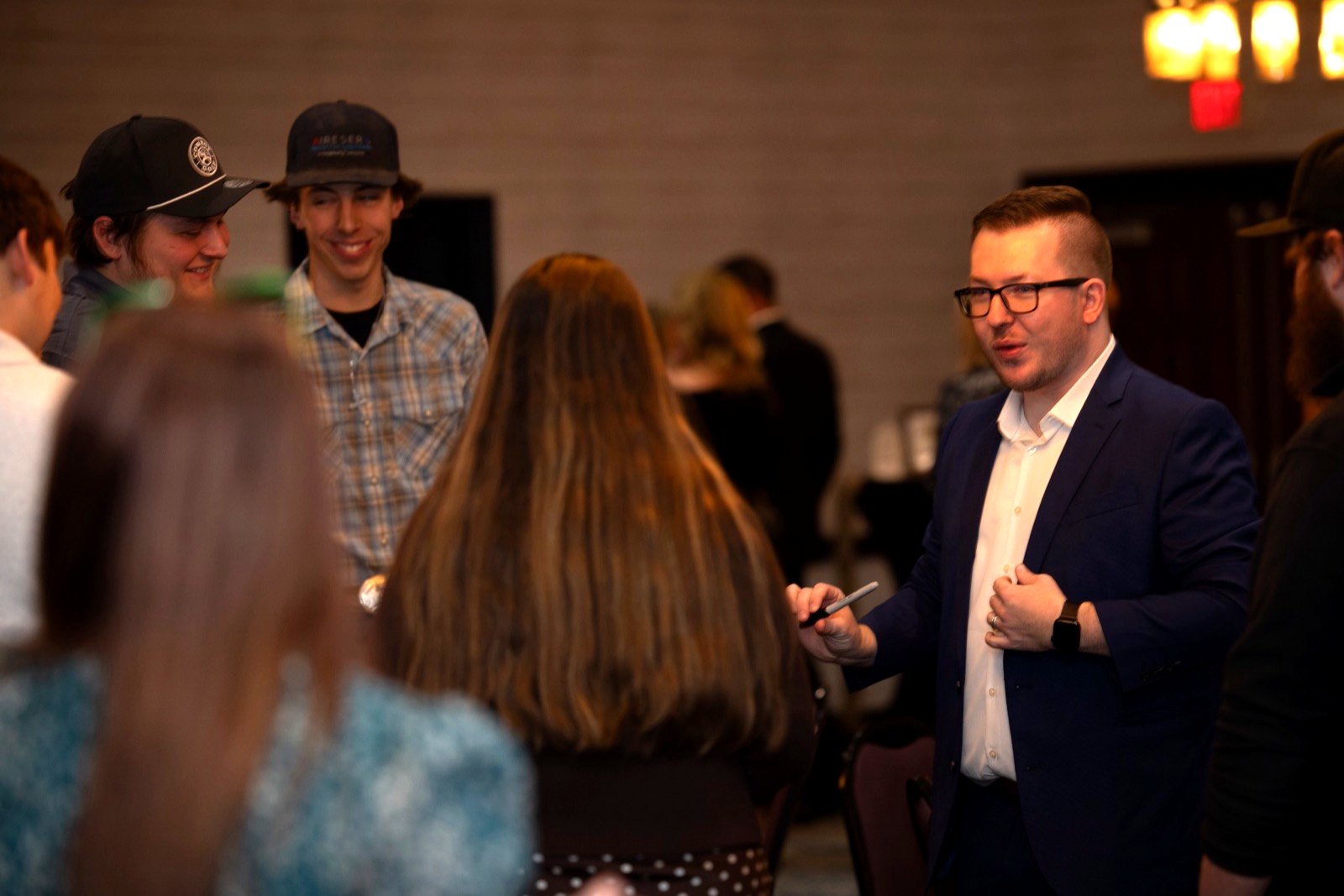 Tyler performing close-up magic for a circle of coworkers at a company reception
