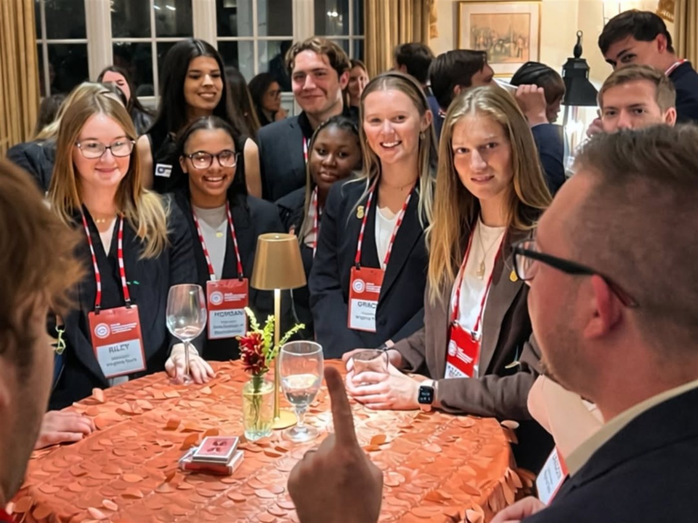 Guests gather around the table at an elegant evening reception as Tyler performs close-up magic
