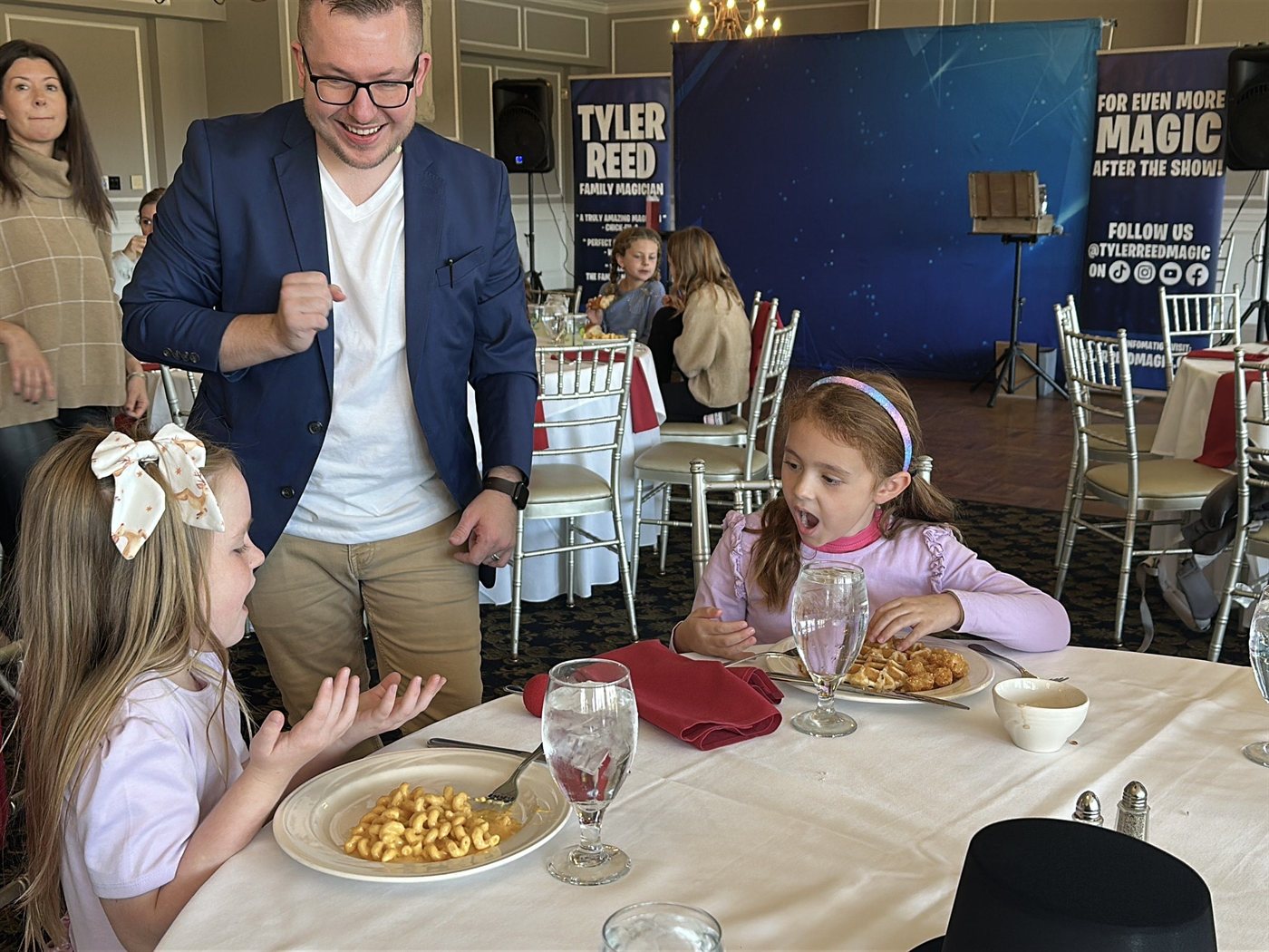 Two kids gasp at the table during a club family lunch as Tyler works the card