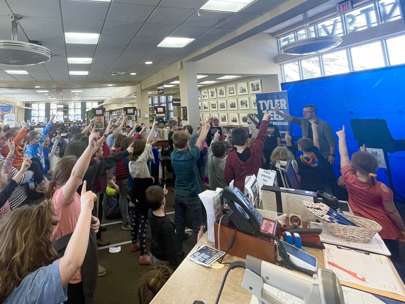 A library packed with families, every hand in the air during the show