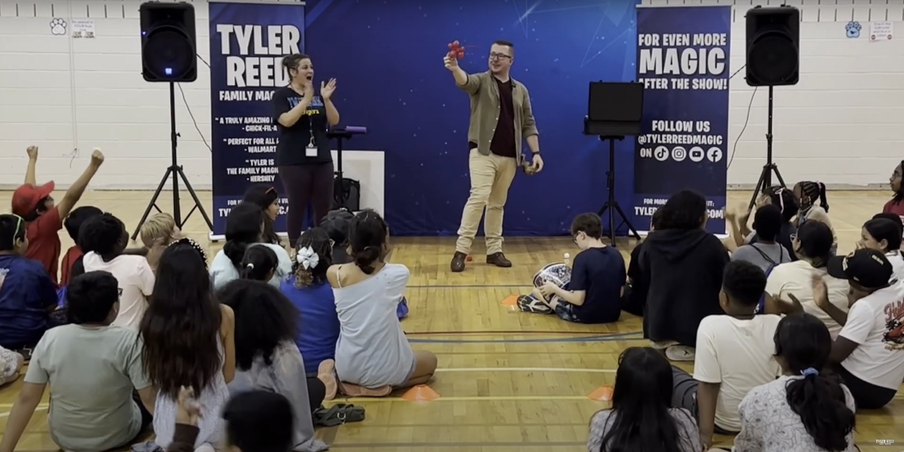 Students cheer from the gym floor as Tyler performs on the assembly stage